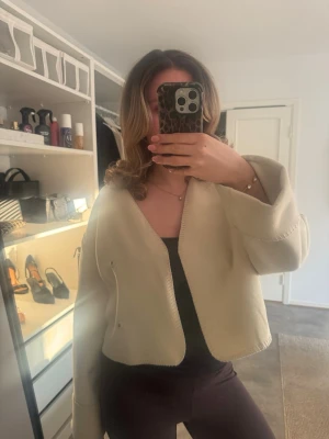 Beige kofta från Gina Tricot - Säljer en beige kofta från Gina Tricot i storlek S. Koftan är croppad med vida ärmar och har synliga sömmar längs kanterna. 