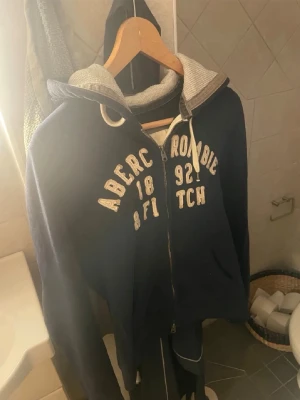 Vintage Abercrombie & Fitch Hoodie - Säljer denna feta vintage A&F hoodien. Den är gammal från runt 2000-talet (min pappas) så den har krymt lite genom åren. Det står M i tröjan men passar S eller XS bättre. Den har ingen visuell defekt den har någon blå liten färgfläck på insidan (jag hittar den inte har bara fått complaints. Men men. Kontakta vid mer frågor 