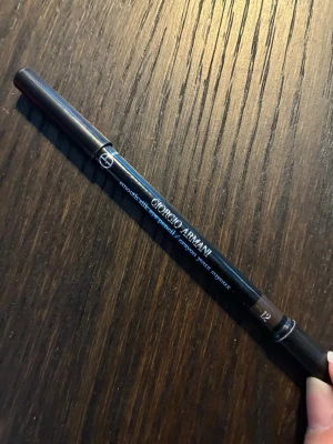 Giorgio Armani brun eyeliner - Snygg brun eyeliner smooth eye silk pencil från Giorgio Armani i nyansen 12. Pennan har en klassisk träkropp med svart finish och dubbla lock, samt en sudd i ena änden för mjukare linjer. Perfekt för att skapa definierade eller sotade ögonlooks. Nästan helt ny. 