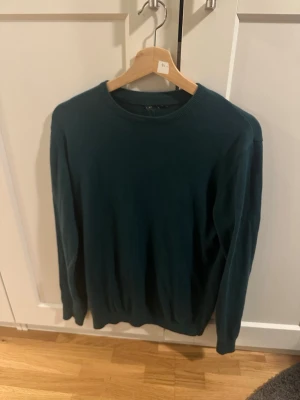 Mörkgrön stickad från Arket - Snygg mörkgrön stilig crewneck från Arket. Lappen är bort klippt eftersom den hängde löst så man ser inte vart tröjan är ifrån, men den är köpt i butik ifrån Arket. Passar perfekt över en skjorta eller mer casual på skola/jobb. Passar allt ifrån 171-178 ungefär, lite berodne på vikt och hur man vill att den ska sitta.