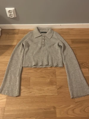 Beige ribbad croppad pikétröja - Säljer en beige ribbad croppad pikétröja från Mango. Tröjan har lång ärm, klassisk krage och knappar framtill. Perfekt till höst och vinter för en chill men ändå snygg look.