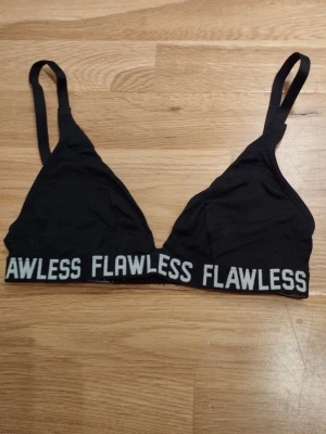 Svart bralette med texten FLAWLESS - Snygg svart bralette med justerbara axelband och bred resår med texten FLAWLESS i vitt runt om. Mjuk och bekväm modell med hakknäppning bak, som passar även för mindre byst. Perfekt för en sportig och avslappnad stil. Från H&M men taggen saknas. Jag har fler annonser uppe och ger mängd rabatt, så kolla gärna min sida!