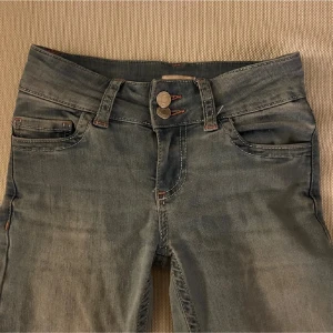 Blåa nelly jeans - Ljusa lågmidjade jeans från nelly med rosa detaljer på fickorna. I storlek 32 men de är uppsydda så skulle säga att de passar någon som är runt 155cm. Pris kan diskuteras🥰