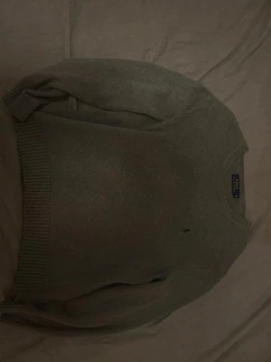 Stickad ralph lauren tröja - En riktigt snygg stickad ralph lauren tröja i en fräsch grå färg med mörkgrön broderi på loggan. Väldigt bra skick inga konstigheter. Står storlek M men skulle säga att den passar den som bär small. Vid andra frågor o funderingar är de bara att skriva