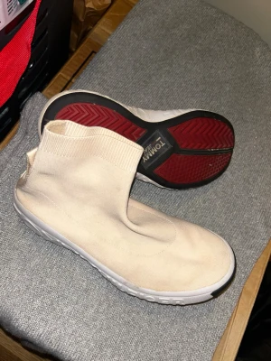 Beige sneakers Tommy Jeans sock-modell - Säljer ett par beige sneakers från Tommy Jeans i stickad sock-modell. Skorna har vit sula med tydlig logga, röda detaljer undertill och breda flärpar bak med texten TOMMY och JEANS. Superstretchigt material och rund tå för en clean look. Lite stenar som har fastnat vilket går att pilla bort, använda 1 gång, lite aprikos färgade 