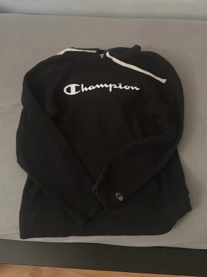 Svart champion hoddie  - Svart Champion hoddie står Champion på den i mitten av tröjan och de är även märke på armen,storlek S men passar M också 