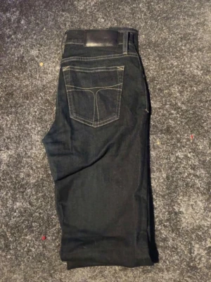 Tiger of Sweden jeans - Snygga mörkblå jeansbyxor med klassisk femficksdesign och kontrastsömmar på bakfickan. Jeansen har rak passform och är tillverkade i slitstarkt denimtyg. Perfekta för dig som gillar en enkel men stilren look. W31