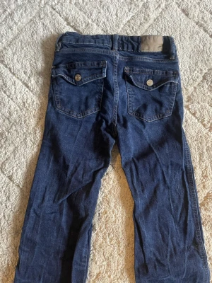 Mörkblå lågmidjade jeans från 157 i XS - Snygga mörkblå jeans från 157 i storlek XS med full längd. Klassisk femficksmodell med två bakfickor med lock och knapp, samt detaljerade sömmar. Jeansen har normal passform och är tillverkade i mjukt denimtyg.