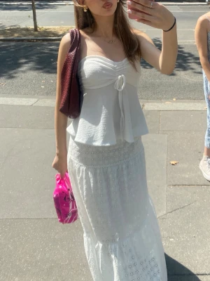 Vit topp med knyt - Supersöt vit bandeau topp med knyt framtill och lätt volang nertill. Storlek s men passar också xs.  Den är köpt utomlands!