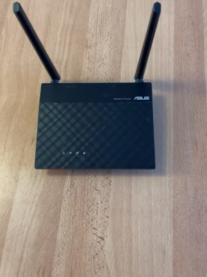 ASUS Wireless N Router - Stabil ASUS Wireless N Router med två antenner för stark täckning. Utrustad med fyra LAN-portar och en WAN-port. Enheten är i gott skick med endast mindre ytliga märken. Perfekt för hemmanätverk eller mindre kontor.