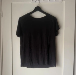 Svart basic t-shirt i bomull - En enkel svart t-shirt med rund hals och korta ärmar. Tillverkad i mjuk bomull, perfekt för en clean och avslappnad stil. Passar dig som gillar minimalistiskt och klassiskt. Snygg att matcha med jeans eller shorts.