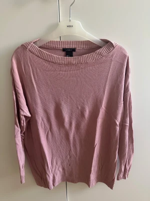 Puderrosa stickad tröja med ribbad kant - Mysig puderrosa stickad tröja med avslappnad passform. Tröjan har långärmade och en bred, ribbad halsringning samt ribbad nederkant. Perfekt för dig som gillar enkel och chill stil. Snygg att matcha med jeans eller kjol