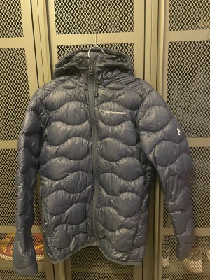 Mörkblå dunjacka Peak Performance S - En peak performance dunjacka i storlek s. En tunnare variant av dunjacka. Har tappat lite puff i höger ärm. 