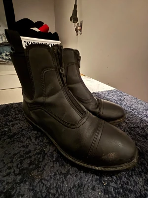 Svarta ridskor med dragkedja - Snygga svarta ridskor i skinn med rund tå och praktisk dragkedja framtill. Perfekta för ridning och har en stilren design med diskreta sömmar. Platt sula för bekväm känsla och klassisk look. Väl använda utan några större skador. STR 39. Hör av er via mejl eller SMS då ja nt kan ta emot Swish på detta nmr e-mejl emli.com@icloud.com mobil-0728875624 mvh Emilia/marina😊