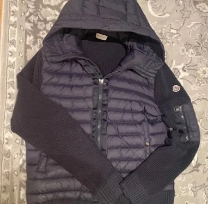 Mörkblå Moncler dunjacka med huva - Säljer en mörkblå dunjacka från Moncler med stickade ärmar och huva. Skicka Gärna bud priset kan sänkas vid snabb försäljning.😁