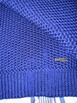 Mörkblå stickad halsduk från Dsquared2 - Snygg och grovstickad mörkblå halsduk från Dsquared2, tillverkad i Italien av 100% virgin ull. Halsduken har en chunky struktur och en metallbricka med logga. Perfekt för att ge din vinterstil en cool touch. Passar perfekt för att lyfta din outfit med en modern och exklusiv accessoar. Halsduken är köpt från NK och är sparamt använd med inga difekter. Tveka inte på att fråga och både prisförslag och bytten godtas