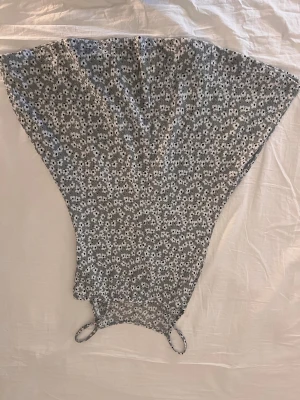 Blommig grå klänning från New 21 - Supersöt grå klänning med vita och svarta blommor från New 21. Klänningen har smala axelband och en luftig, utställd form som ger en cool och avslappnad vibe. Perfekt för varma dagar när du vill känna dig både bekväm och snygg.