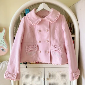 Rosa lolita kappa  - Supersöt ljusrosa sweet lolita kappa från Chess Story med rosetter fram, bak och på ärmarna. Jackan har spetsdetaljer vid kragen och nederkanten. 💖 Kinesisk storlek L men uppskattas som 36/38, kanske upp till 40 i EU storlekar 💖