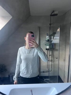 Grå sweatshirt från Calvin Klein Jeans - Säljer en stilren grå sweatshirt från Calvin Klein Jeans med vit logga framtill. Tröjan har rund hals, långa ärmar och ribbade muddar vid ärmslut och nederkant. Perfekt för en chill och snygg look.