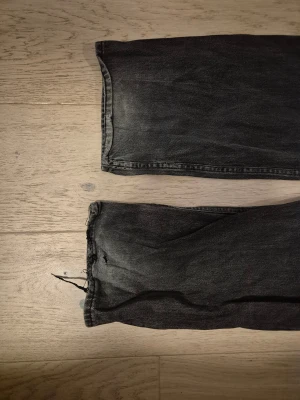 Svarta loose fit jeans från H&M - Svarta jeans med tvättad look från H&M. Loose fit-modell med raka ben och klassiska fem fickor. Lite slitet längst ner på benet (se bild)