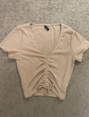 Beige tröja med detalj - Beige T-shirt med knyt-detalj på framsidan. Tröjan är i storlek S från H&M