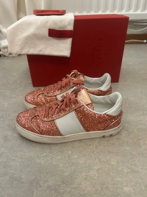 Valentino Flycrew  - Säljer ett par Valentino Flycrew sneakers i befintligt skick med rosa glitter. Kommer med originalkartong, dustbag och extra skosnöre medkommer. 3 nitar har fallit av, hör av dig vid övriga frågor.