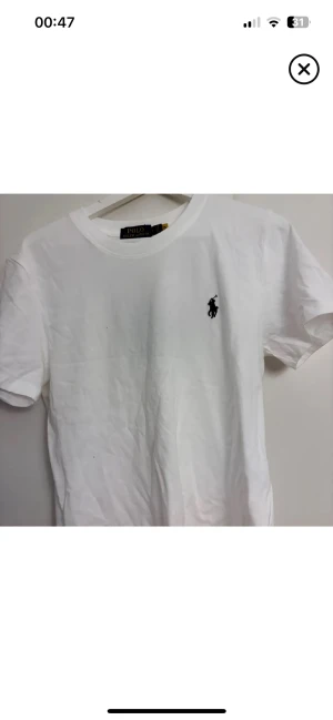 Vit t-shirt från Polo Ralph Lauren - Vit t-shirt storlek M från Polo Ralph Lauren med klassiska svarta Polo-loggan broderad på bröstet och är gjord i mjuk bomull. Enkel och stilren design som funkar till allt. Aldrig använd!!!! Skriv vid funderingar!!!!!