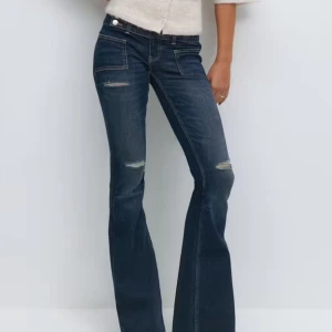 Lågmidjade jeans - Ifrån Gina Tricot 14+ i storlek L och TALL, så extra långa, små i storlek. 80cm midja, 84 i innerbenslängd. Helt oanvända med lappar kvar.                                               Snygga mörkblå jeans med bootcut passform och slitna detaljer vid knäna. Jeansen har två framfickor med markerade sömmar och dubbla knappar i midjan. Materialet är klassisk denim som ger en cool och avslappnad look.