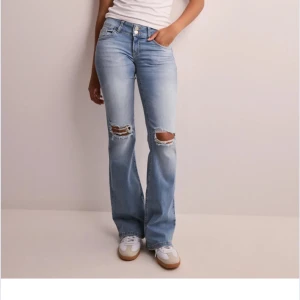 Nelly Liw Waist jeans - Ljusblå low waist jeans från Nelly. Fickor iblak och slitna vid knäna ifram. Köpta för 700kr och endast använda några gånger, som nya inga defekter alls.