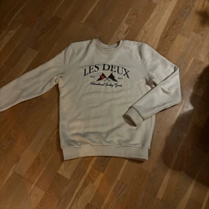 Beige sweatshirt från Les Deux - Säljer en beige sweatshirt från Les Deux med tryck framtill. Tröjan har rund hals, ribbade muddar och är långärmad. Perfekt för dig som gillar stilrena och bekväma plagg med snygg logga på bröstet. Storlek 164 men passar både M och S utan problem 