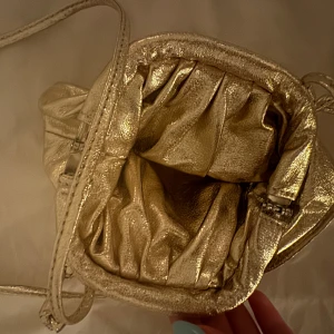 Guldig väska  - En Guldig axelremsväska, aldrig använd. Köpt här på plick
