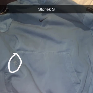 Ljusblå Nike hoodie med huva - Säljer en ljusblå hoodie från Nike med klassisk svart swoosh på bröstet. Tröjan har huva och stor magficka framtill. Perfekt för chill dagar eller när du vill ha en sportig look.