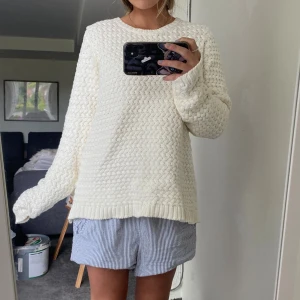 Vit stickad tröja - Mysig vit stickad tröja med grovt strukturmönster och rund hals. Tröjan har långa ärmar och ribbade muddar vid ärmslut och nederkant. Perfekt för lager-på-lager och chill dagar.