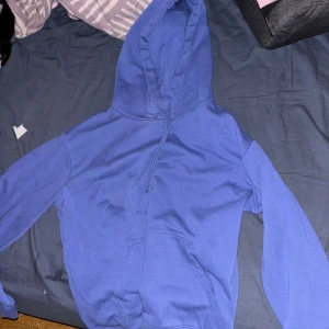 Blå hoodie med huva och ficka - En enkel blå hoodie med huva och dragsko. Tröjan har en stor magficka framtill och långa ärmar. Perfekt för chill dagar eller när du vill ha något bekvämt och stilrent. Materialet känns mjukt och passar bra till vardagslooken. Priset går att diskutera! (nypris 199)