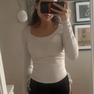 Vit långärmad topp med snörning - (Välj 3 plagg för 70kr - gäller alla plagg som kostar mellan 20-40kr) Säljer en vit långärmad topp med rundad urringning och snörningsdetaljer i sidorna. 