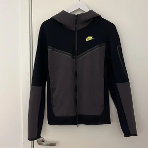 Nike tech lime green/black XS - Nike techen är i väldigt bra skick och har inte använts på länge eftersom den inte passar min stil längre. Säljes inte längre förutom från återsäljare så man kan säga att den var limited edition. Storlek XS. Köptes för 1299kr från NIKE’s officiella hemsida. Är äkta. Pris kan diskuteras. Tar ej byten.