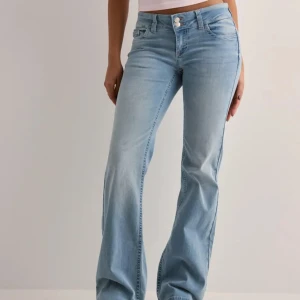 Nelly bootcut jeans💕 - Säljer ett par ljusblå bootcut jeans från Nelly med fina rosa sömmar på bakfickorna. Jeansen har låg midja och är tillverkade i mjukt denimtyg med lite stretch. 
