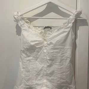 Elena topp vit - Supersöt vit blus från Brandy Melville med volangdetaljer på axelbanden och v-ringning. Endast använd 2 gånger🩷 Skriv till mig privat om ni behöver nån mer information🥰 Den är onesize men skulle säga att den är XS-S. Jag kan även byta den här till rosa!