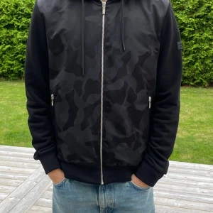 Karl Lagerfeld cardigan - Säljer en svart cardigan från Karl Lagerfeld med svart camouflagemönster. Toppenskick och inga slitage eller hål. Storlek S.  Nypris 4200