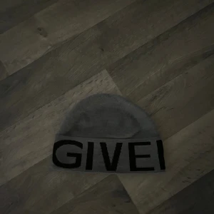 Grå mössa från Givenchy i ull - Snygg grå mössa från Givenchy i mjuk ull med bred svart logotyptext runt hela kanten. Klassisk beanie-modell som sitter skönt på huvudet och ger en stilren look. Perfekt accessoar för att lyfta din outfit med exklusiv känsla.