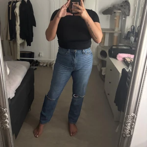 Blåa raka jeans från HM - Säljer ett par klassiska blå jeans från HM med raka ben och hög midja. Jeansen har en snygg sliten detalj vid knät.
