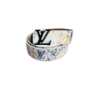 Louis Vuitton bälte  - Snyggt vitt bälte från Louis Vuitton med färgglada LV-loggor och svart LV-spänne. Bältet har en unik och trendig design som sticker ut och passar perfekt för dig som vill ha något extra. Materialet är exklusivt och bältet har en modern känsla.