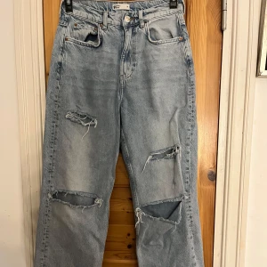 Ljusblå ripped jeans straight fit - Ljusblå jeans från Gina Tricot med raka ben och flera stora ripped detaljer på låren och knäna.