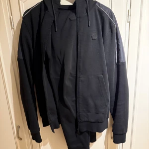 Svart tracksuit från Cruyff   - Säljer en svart tracksuit från Cruyff. Perfekt för en sportig och avslappnad stil. Tröjan är storlek S och byxan M