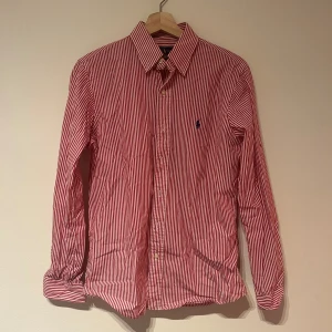 Rödvit randig skjorta från Ralph Lauren - Välskött Ralph lauren skjorta, men vad förväntar man sig egentligen av Ralph Lauren han själv! Bra kvalitet och har mycket kvar att ge! Storlek S. Vid fler frågor eller modellbilder skicka PM!