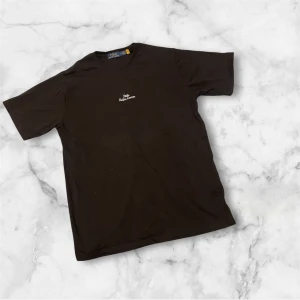 Ralph Lauren T-shirt  - Svart t-shirt från Polo Ralph Lauren med vit broderad logga på bröstet. Klassisk rund halsringning och korta ärmar. Tillverkad i mjuk bomull för en skön känsla och enkel stil.