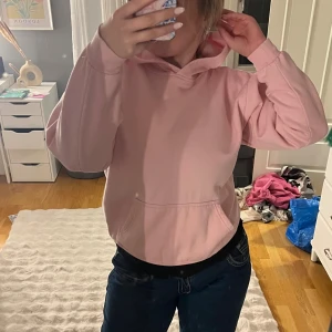 Ljusrosa hoodie från YOU Classic - Mysig ljusrosa hoodie från YOU Classic i storlek S. Tröjan har huva, magficka och är tillverkad i mjukt fleecematerial. Perfekt för chill dagar eller när du vill vara extra bekväm. Långärmad och loose passform.