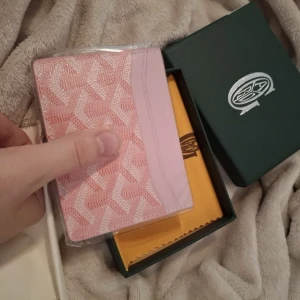 Rosa plånbok med mönster  - Säljer en snygg rosa Plånboken har flera kortfack och levereras i originalask med tygpåse. Perfekt accessoar för dig som gillar stilrena detaljer och vill ha något unikt i väskan.