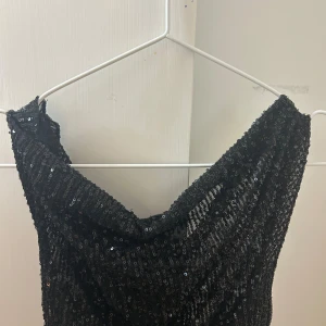 Svart glittrig paljett topp - Säljer en svart, glittrig topp täckt av paljetter. Säljs inte längre i original butik längre (Gina)! Säljer då den är förliten. 