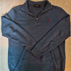 Stickad ralph lauren half zip  - Blå stickad tröja från Polo Ralph Lauren med half zip och hög krage. Klassisk röd logga broderad på bröstet. Långärmad modell med ribbade muddar och nederkant. Perfekt för lager-på-lager och snygg till jeans. Notera att den är blå vilket ej syns  superbra på bilderna, be om nya bilder om du vill se! Pris går att diskutera 🤝